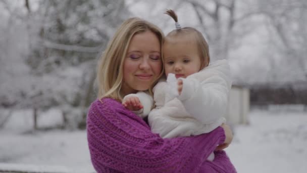 Joven mujer rubia con su linda niña disfrutando en el parque de nieve — Vídeos de Stock