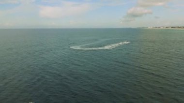 Sahile yakın seyreden bir motorlu teknenin havadan görüntüsü.