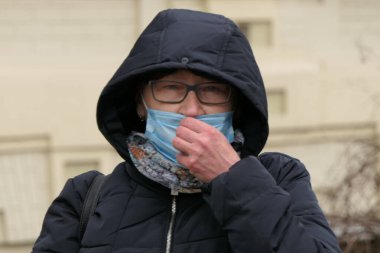 Kiev, Ukraine - March, 16, 2020: a fearful woman in glasses, a hood and a mask.