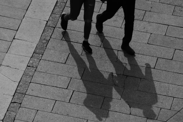 一个男人和一个女人站在石路上 一个穿牛仔裤 有三个洞的女孩和一个穿黑裤子 膝盖以上的男人的影子 — 图库照片