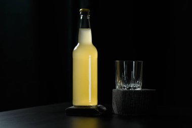 Bir şişe portakal suyu, limonata, alkollü içecek ve siyah tahta masanın üzerinde duran boş bir bardak. Organik detoks ya da sağlıksız içki konsepti. Metin için yer.