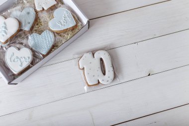 Present box and gingerbread cookies. Hearts and number 10 shapes. Sweets on white wooden background. 14 February Valentine's day and number ten concept. Place for text.