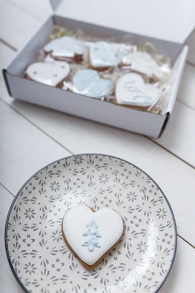 Heart shape gingerbread cookie on plate standing on white wooden table background. 14 February Valentine\'s day and love concept. Present box and gingerbread cookies.  Place for text.