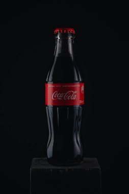 İzmail, Ukrayna - 13 Mart 2020. Siyah arka planda Coca Cola şişesi. Ahşap masada bir şişe kola..