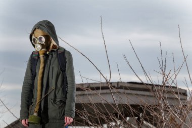 Gaz maskeli insan harabeler ve dramatik gökyüzü arkaplanı arasında duruyor. Çevresel kirlilik, ekoloji felaketi, radyasyon, biyolojik tehlike kavramı.