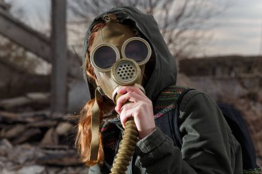 Harabeler ve dramatik gökyüzü geçmişi arasında gaz maskeli bir insan. Çevresel kirlilik, ekoloji felaketi, radyasyon, biyolojik tehlike kavramı.