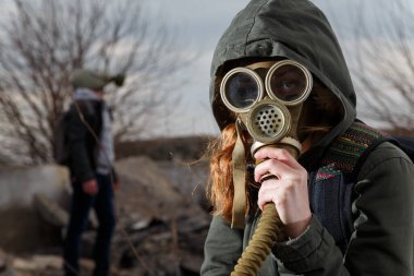 Harabeler ve dramatik gökyüzü geçmişi arasında gaz maskeli bir insan. Çevresel kirlilik, ekoloji felaketi, radyasyon, biyolojik tehlike kavramı.