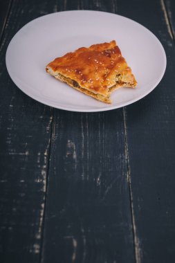 Isırılmış et parçası ve siyah ahşap zemin üzerinde beyaz tabakta havuçlu turta. Lezzetli sağlıklı yiyecekler. Diyet, beslenme, yeme alışkanlıkları. Metin için yer