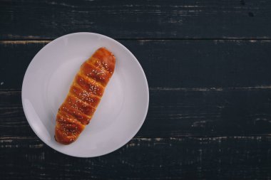 Siyah ahşap arka planda beyaz tabakta yuvarlanmış elmalı turta. Lezzetli sağlıklı yiyecekler. Diyet, beslenme, yeme alışkanlıkları. Metin için yer.
