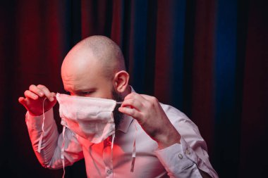 Beyaz gömlekli adam el yapımı gazlı bez maske takıyor. Korku ve acı hissi. Sağlık, solunum hastalıklarının önlenmesi, virüs enfeksiyonlarının önlenmesi, COVID-19 konsepti.