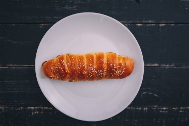 Siyah ahşap arka planda beyaz tabakta yuvarlanmış elmalı turta. Lezzetli sağlıklı yiyecekler. Diyet, beslenme, yeme alışkanlıkları. Metin için yer.