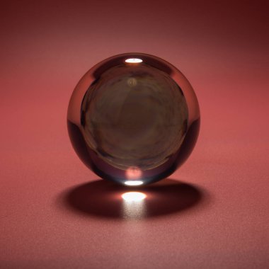 Pembe arka planda cam bir topun içindeki deniz kabuğu