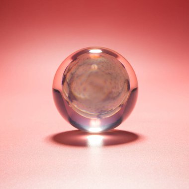 Pembe arka planda cam bir topun içindeki deniz kabuğu