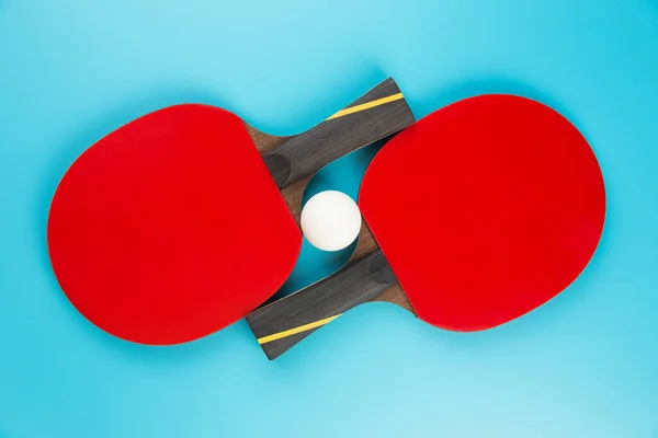 Tenis raketleri ve mavi arka planda pinpon topu.