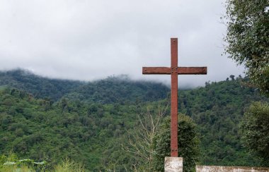 Wooden cross on lush mountain top. clipart