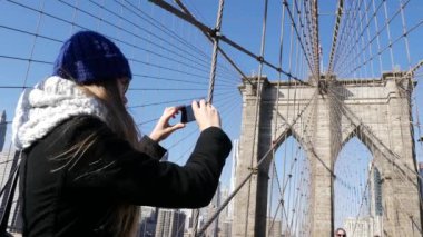 Genç kadın turist çekim onun akıllı telefon ile Brooklyn Köprüsü Nyc üzerinde