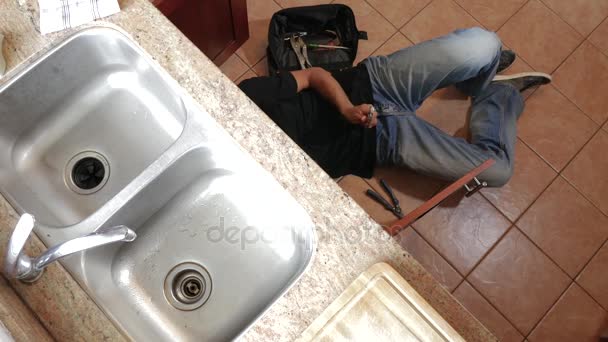 Klempner repariert die Spüle in einer Küche, die auf dem Boden liegt