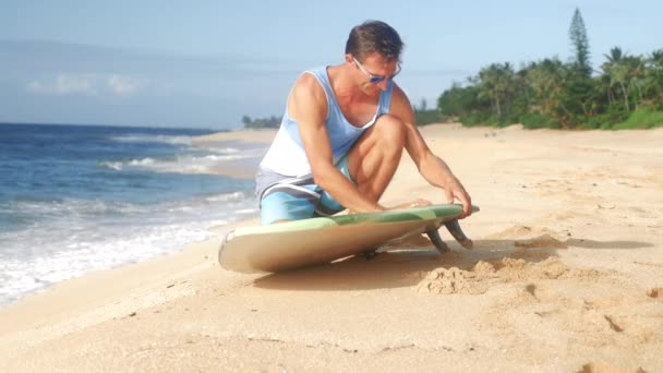 A surfer waxing board before surfing Hawaii — Stock Video
