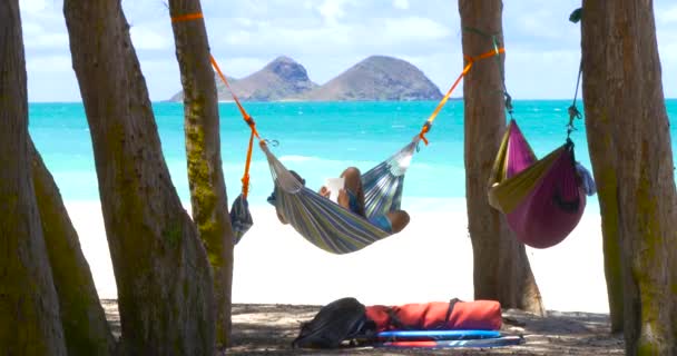 Jeune homme lisant un livre sur la plage exotique d'hamac — Video