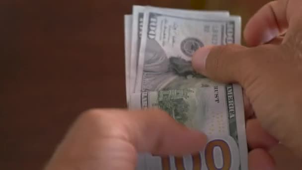 Nahaufnahme eines Geschäftsmannes, der Hundert-Dollar-Scheine in der Hand hält — Stockvideo