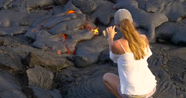 Девушка фотографирует текущую лаву в вулкане Килауэя на Гавайях — стоковое видео