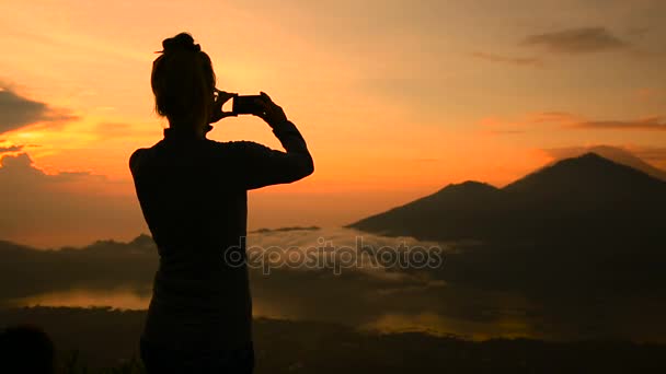 Chica tomando fotos del amanecer sobre el lago Batur, Volcán Agung y Abang, Bali — Vídeos de Stock