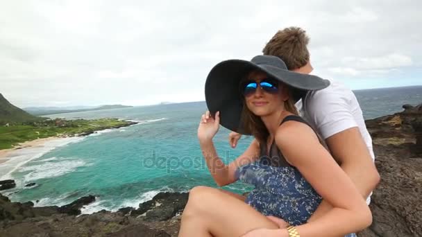 Pareja activa joven sentada y mirando a la vista en Makapuu Lookout, Oahu, Hawaii — Vídeo de stock