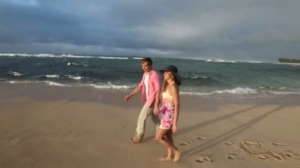 Любящие молодые кавказские пары держатся за руки, идя вместе по пляжу Оаху Гавайи — стоковое видео