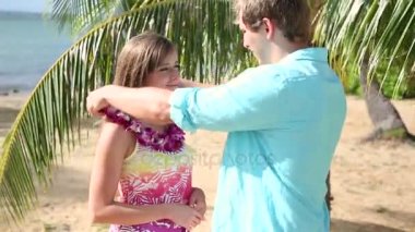 Genç adam beach adlı kadının boynuna pembe orkide Lei çelenk koyarak