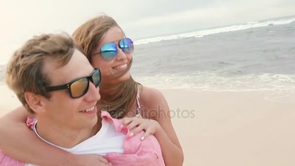 Sonriente joven pareja a cuestas en la playa — Vídeo de stock