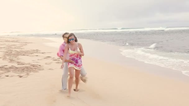 Attraktiva friska par att ha kul tillsammans som körs på stranden — Stockvideo