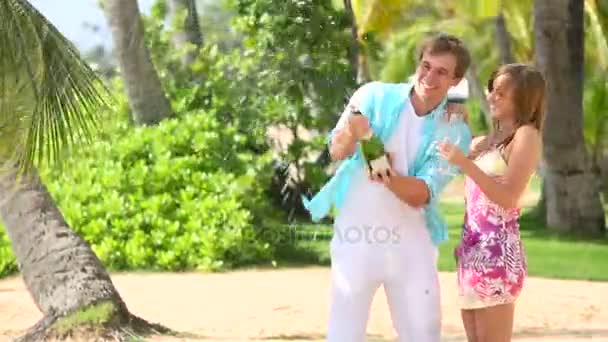 若い幸せなカップルがビーチでシャンパンのコルクをポップ — ストック動画