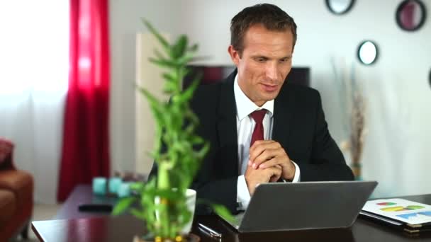 A young businessman is engaged in a video call with a client at home — Stock Video