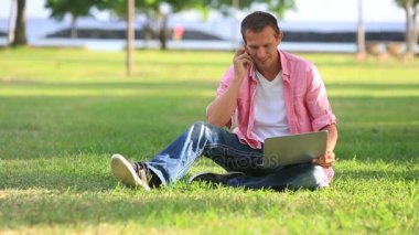 Laptop üstünde hareket eden telefon parkta konuşma ile adam