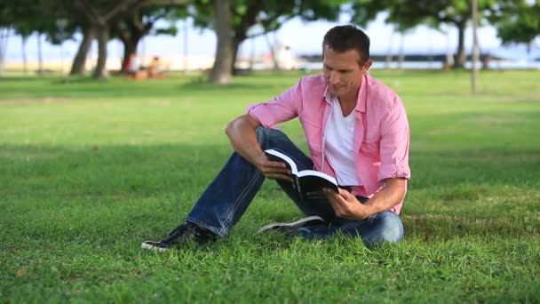 Relaxado homem leitura livro no parque — Vídeo de Stock