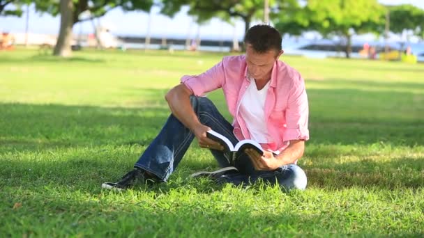 Rilassato uomo lettura libro nel parco — Video Stock