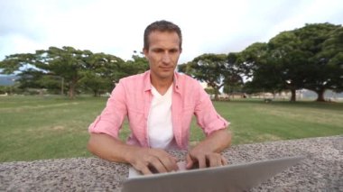 Güleryüzlü parkta bilgisayar kullanan adam