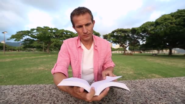 Relaxado homem leitura livro no parque — Vídeo de Stock