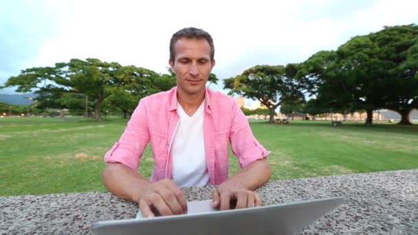Hombre de fresado usando la computadora en el parque — Vídeos de Stock