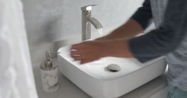 Adam ellerini en iyi şekilde yıkıyor. Coronavirüs suyu duruluyor. Suyu ovuyor, havluyu kurutuyor.