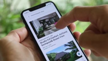 AirBnB kullanıcısı akıllı telefonundaki AirBnB uygulamasını kullanarak kalacak yer arıyor, 4K Video.