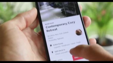 AirBnB kullanıcısı akıllı telefonundaki AirBnB uygulamasını kullanarak kalacak yer arıyor, 4K Video.