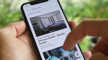 AirBnB kullanıcısı akıllı telefonundaki AirBnB uygulamasını kullanarak kalacak yer arıyor, 4K Video.