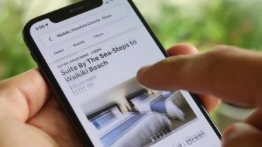 AirBnB kullanıcısı akıllı telefonundaki AirBnB uygulamasını kullanarak kalacak yer arıyor, 4K Video.