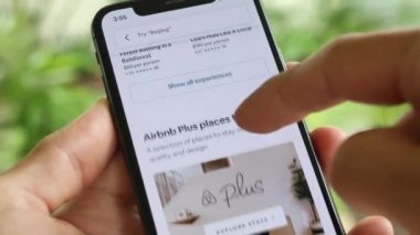AirBnB kullanıcısı akıllı telefonundaki AirBnB uygulamasını kullanarak kalacak yer arıyor, 4K Video.