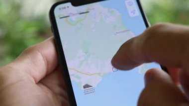 Telefonuyla navigasyon uygulaması kullanan ve Hawaii 'deki popüler yerlere seyahat yolları arayan bir adam. Cep telefonu ekranı yakın çekim. Yol Haritası