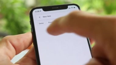 AirBnB kullanıcısı akıllı telefonundaki AirBnB uygulamasını kullanarak kalacak yer arıyor, 4K Video.
