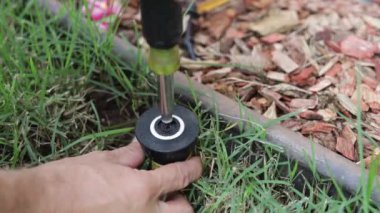 Tesisatçı arka bahçede fıskiye başlığını tamir ediyor. Profesyonel Kafkas Bahçesi Sistemleri Kurucusu 'ndan Çim Sahası Fıskiyeleri Kurulumu. Çim Fıskiyesi Ayarlanıyor.