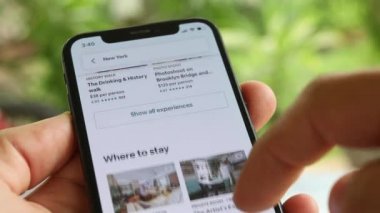 AirBnB kullanıcısı akıllı telefonundaki AirBnB uygulamasını kullanarak kalacak yer arıyor, 4K Video.