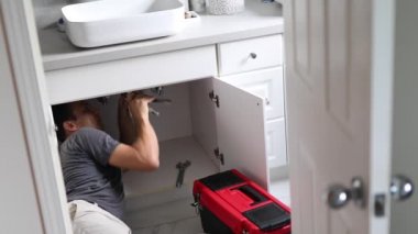 Muslukçu Lavabo 'da çalışıyor. Tuvalette aletleri olan tesisatçı. Tesisat ve Yenileme